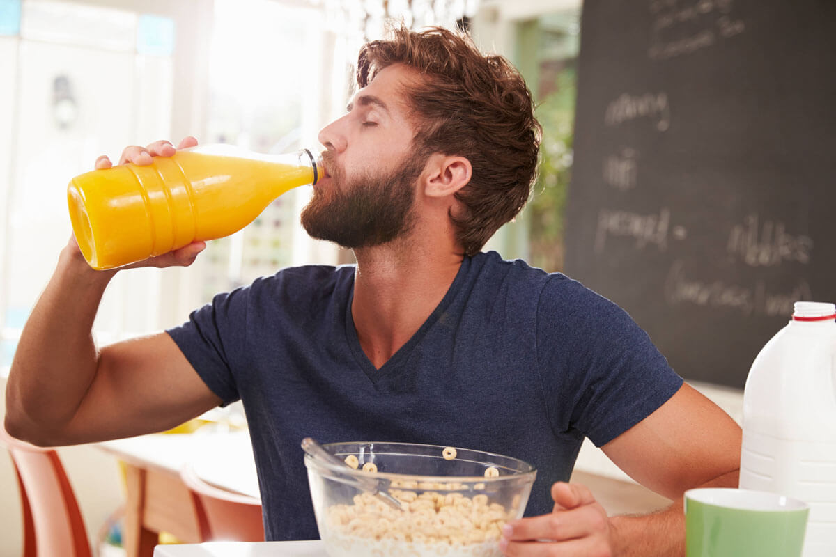 Mann trinkt Orangensaft.